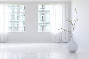 Pair of large bright windows in spacious empty apartment room interior with hardwood floor and large planter with little tree shrub. 3d Rendering.